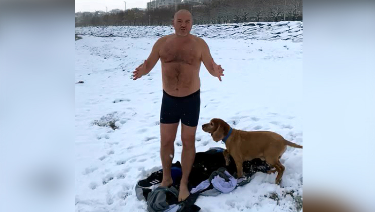 Karlı havaya aldırış etmeden köpeğiyle beraber denizde yüzdü